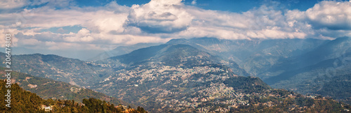 View from the observation deck of the Buddhist monastery Rumtek on the capital of Sikkim - the city of Gangtok and Himalayas under covering clouds. © Dymov