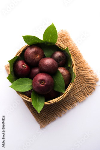 Fresh Kokum or Garcinia indica fruit from India isolated over white or in cane basket with leaves. selective focus photo