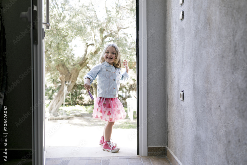 Portrait of laughing little girl standing in front of open entry door Portrait of laughing little girl standing in front of open entry door