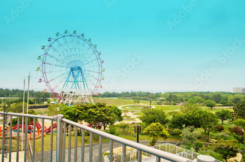 Simple red and blue ferris Wheel with sky background stands on the fresh green grass garden in spring season as a symbol landmark of Uminonakamichi park in Fukuoka city  Kyushu  South of Japan.