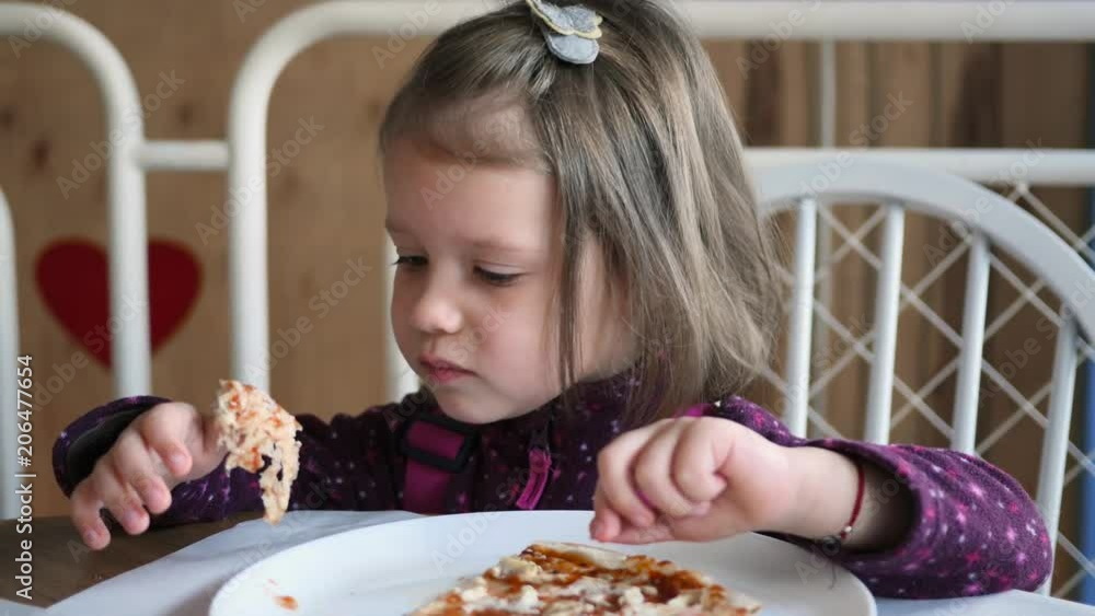 Little kid girl in restaurant try to eat but does not like a food pizza Little kid girl in restaurant try to eat but does not like a food pizza