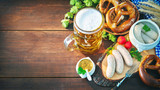 Bavarian sausages with pretzels, sweet mustard and beer mug on rustic wooden table