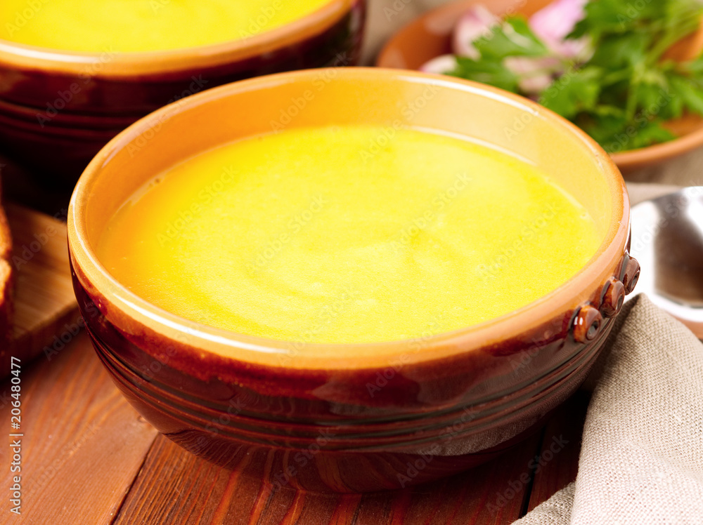 brown bowl of pumpkin soup on brown dark wooden background, side view. brown bowl of pumpkin soup on brown dark wooden background, side view.