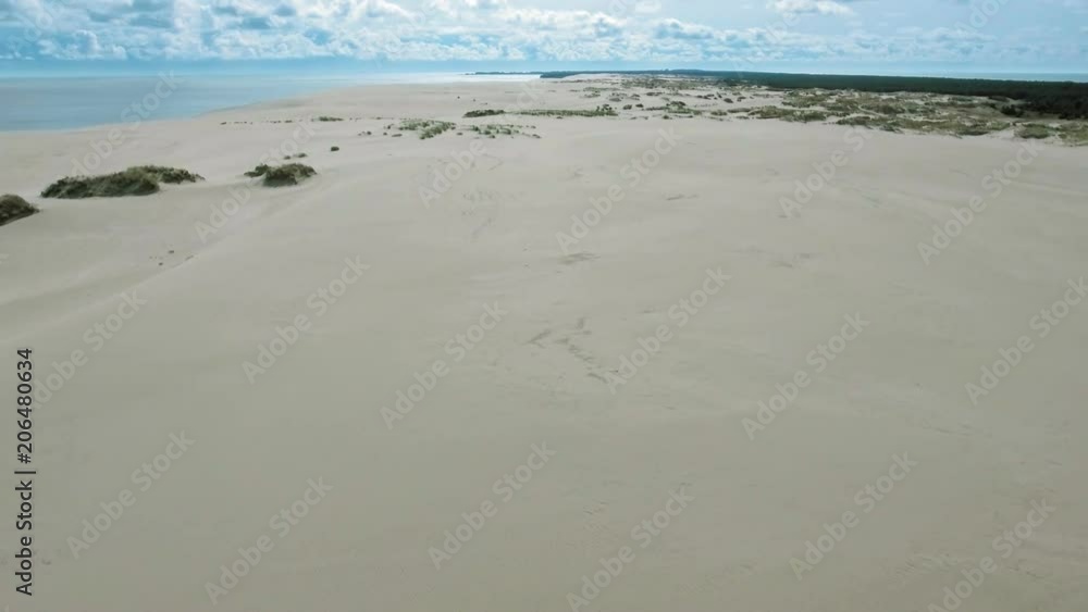 Empty sandy beach with white sand. Texture of sand dunes white color. Sandy surface with hills, green bushes and grass. View from above desert barkhans Empty sandy beach with white sand. Texture of sand dunes white color. Sandy surface with hills, green bushes and grass. View from above desert barkhans