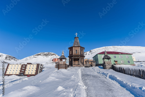 Landscape of the Russian city of Barentsburg on the Spitsbergen archipelago in the winter in the Arctic In sunny weather and blue sky © bublik_polina