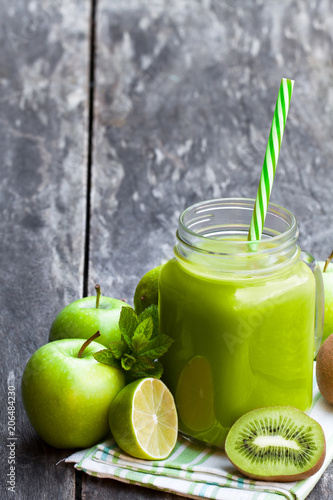 Fresh  smoothie with green fruits in a glass jar mug on wooden table