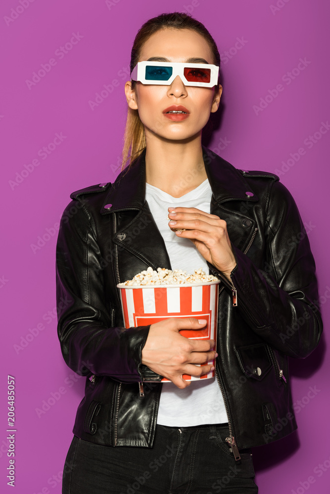 beautiful asian girl in leather jacket and 3d glasses eating popcorn and looking at camera isolated on violet beautiful asian girl in leather jacket and 3d glasses eating popcorn and looking at camera isolated on violet