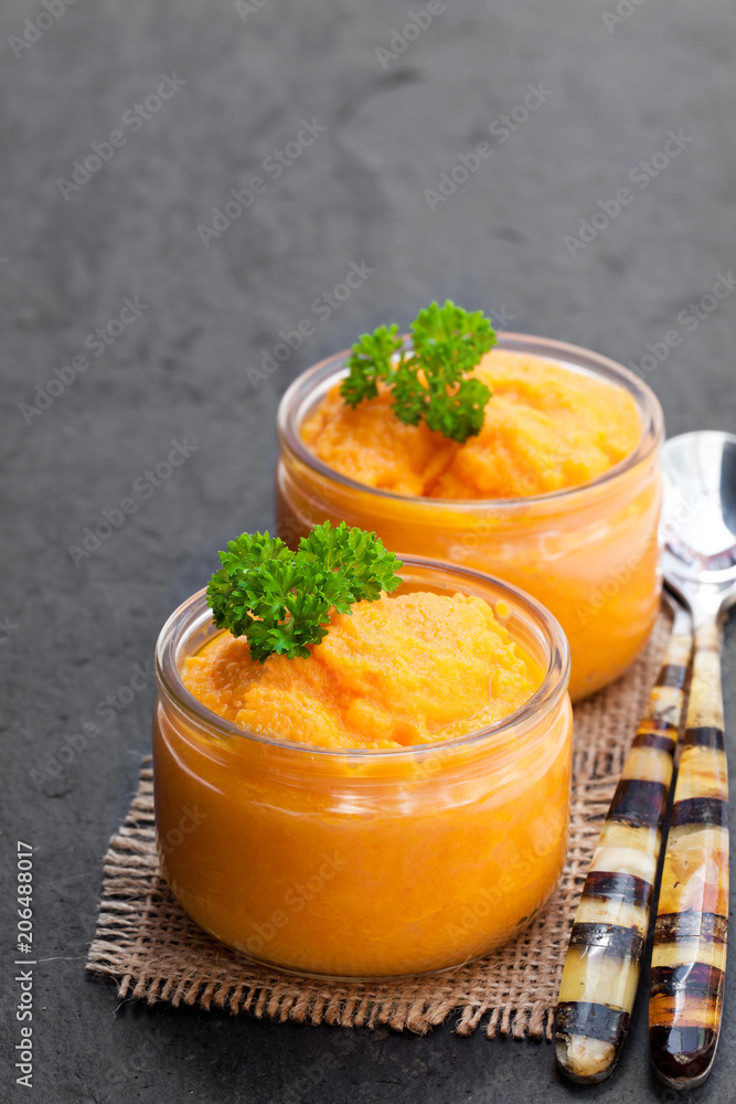 Carrot puree in glass jars on black stone background Carrot puree in glass jars on black stone background