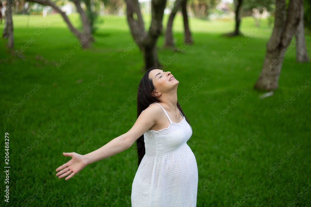 Pregnant couple walks in the park together holding hands Pregnant couple walks in the park together holding hands
