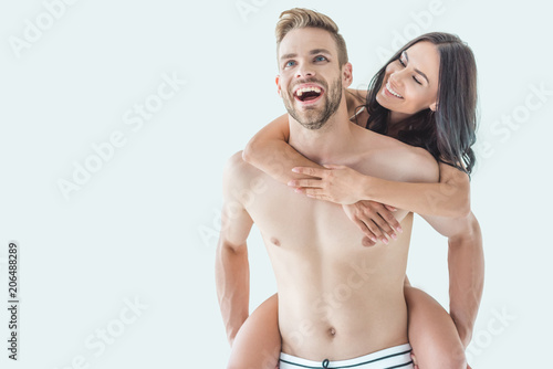 young laughing man piggybacking his beautiful girlfriend, isolated on white