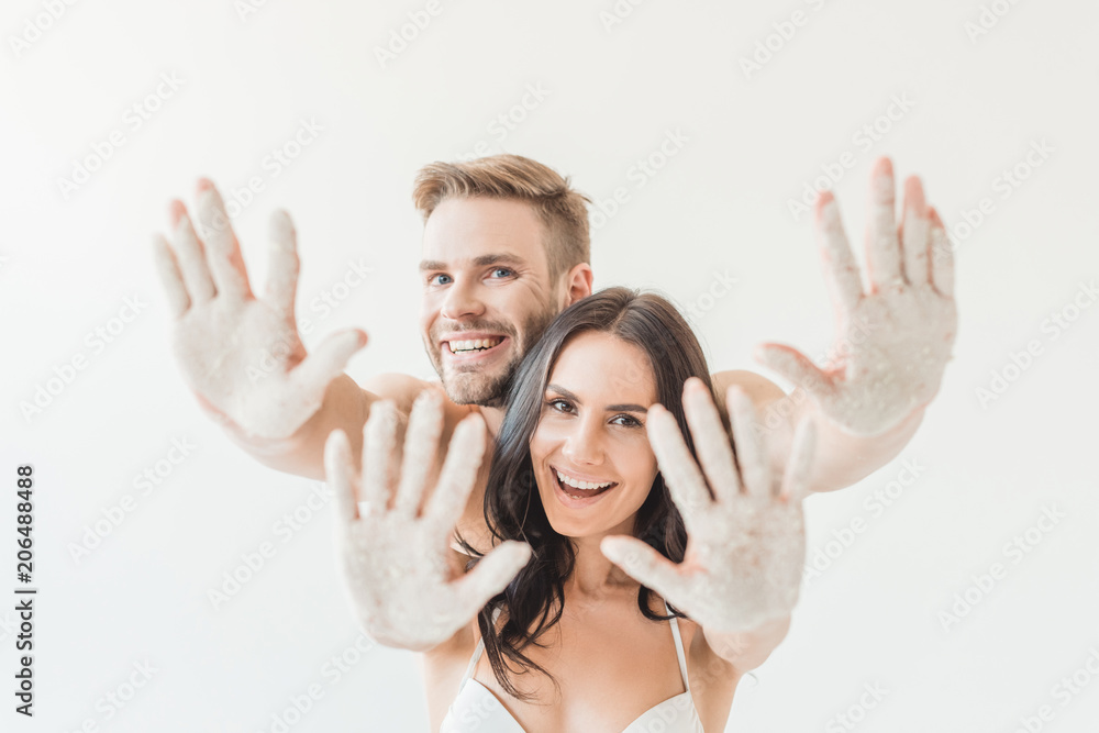 beautiful smiling couple showing hands in sand, isolated on white beautiful smiling couple showing hands in sand, isolated on white