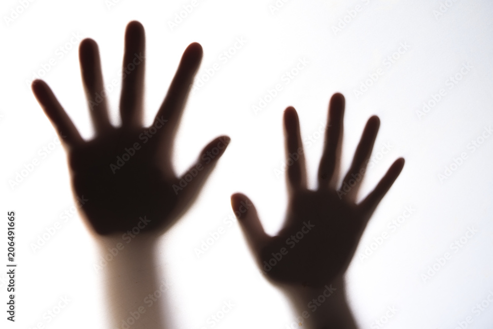 The silhouette of a woman's hand expressing fear.
