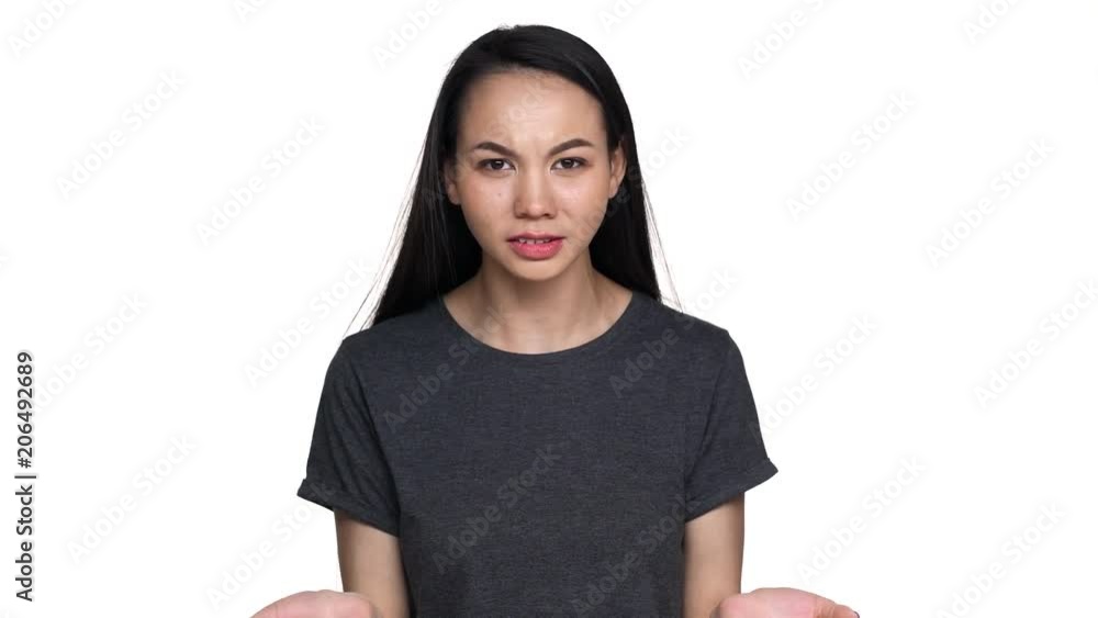 Portrait of brunette annoyed asian woman 20s in casual t-shirt gesturing in furious manner and asking what with aggression, isolated over white background. Concept of emotions
