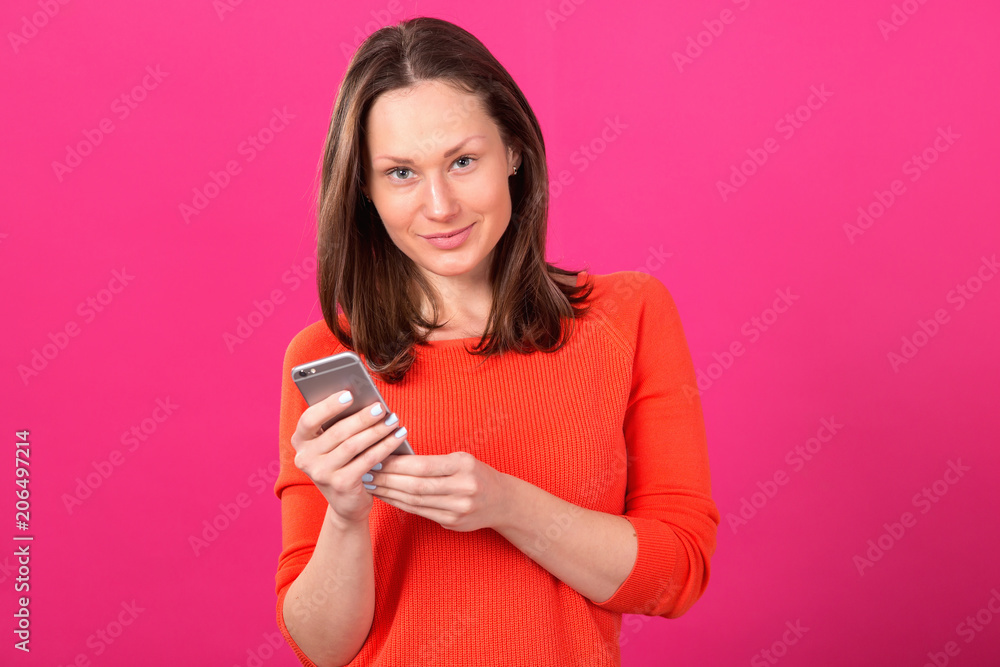 Beautiful brunette woman with smartphone in hands on a pink background. Beautiful brunette woman with smartphone in hands on a pink background.