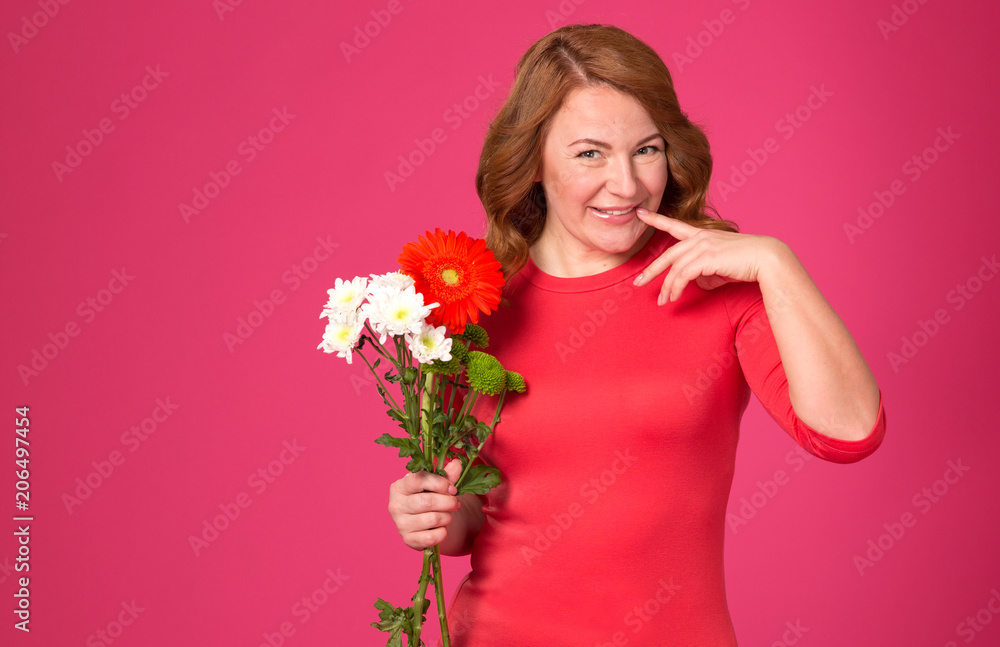 Very happy woman. Beautiful adult woman with flowers on a pink background.