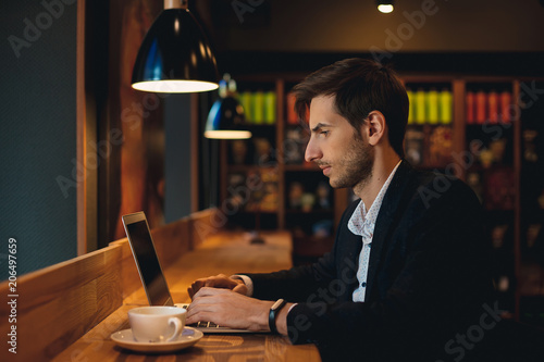 Confident man working on laptop having coffee