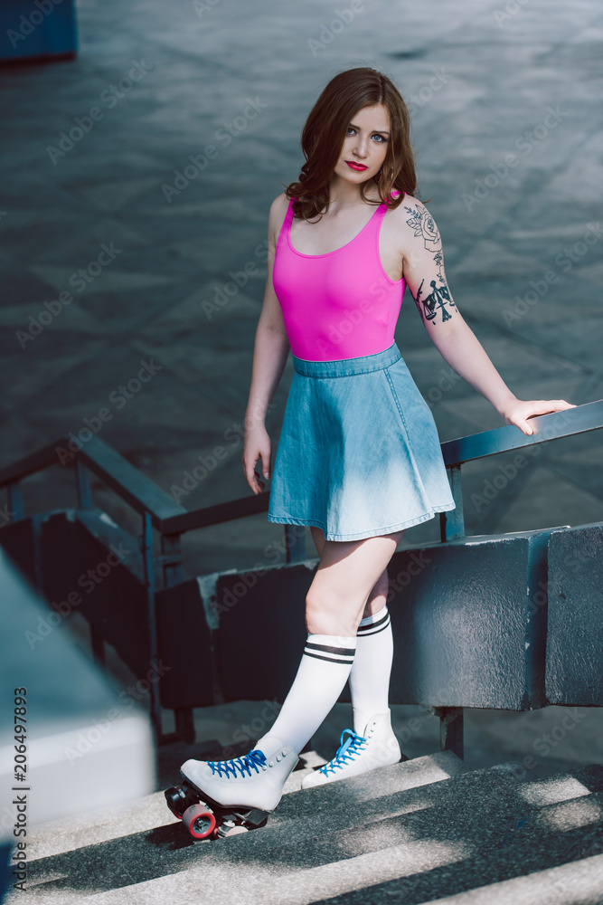 beautiful girl in denim skirt and roller skates standing on stairs and  looking at camera Stock Photo | Adobe Stock