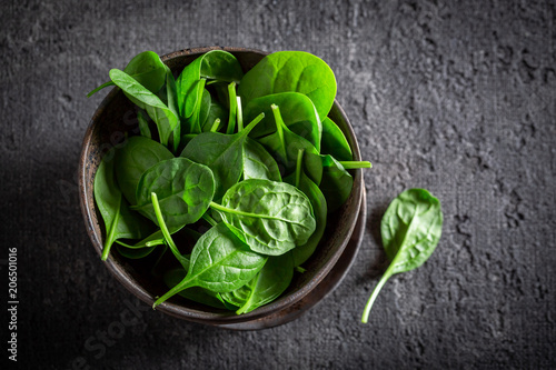Raw green spinach in small rustic bowl