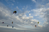 group of wings or kites used to practice kitesurfing, extreme sport, in air on a day of strong wind, blue sky at sunset, light and clouds, spring, ligurian riviera, italy, mediterranean sea