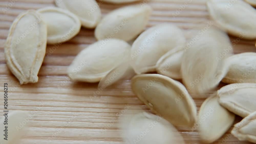 Pumpkin seeds falling on the wooden background Pumpkin seeds falling on the wooden background