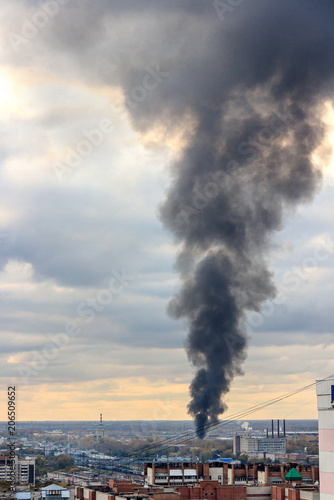 Fire in the city.  black column of smoke rises to sky.
