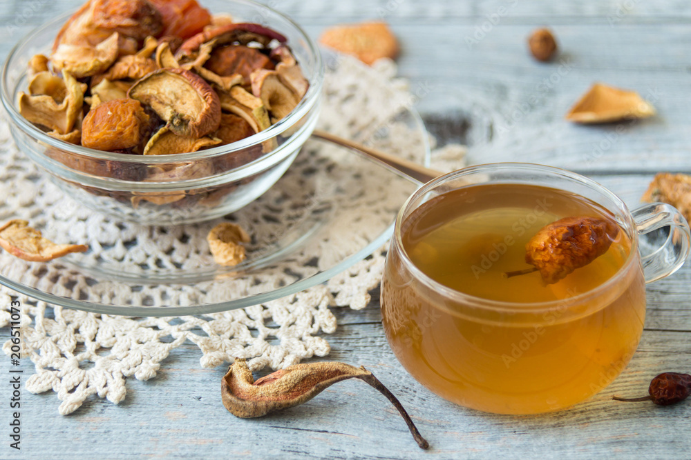 Mug with compote and a mixture of dried fruits in a small round glass bowl on an old wooden table. Mug with compote and a mixture of dried fruits in a small round glass bowl on an old wooden table.