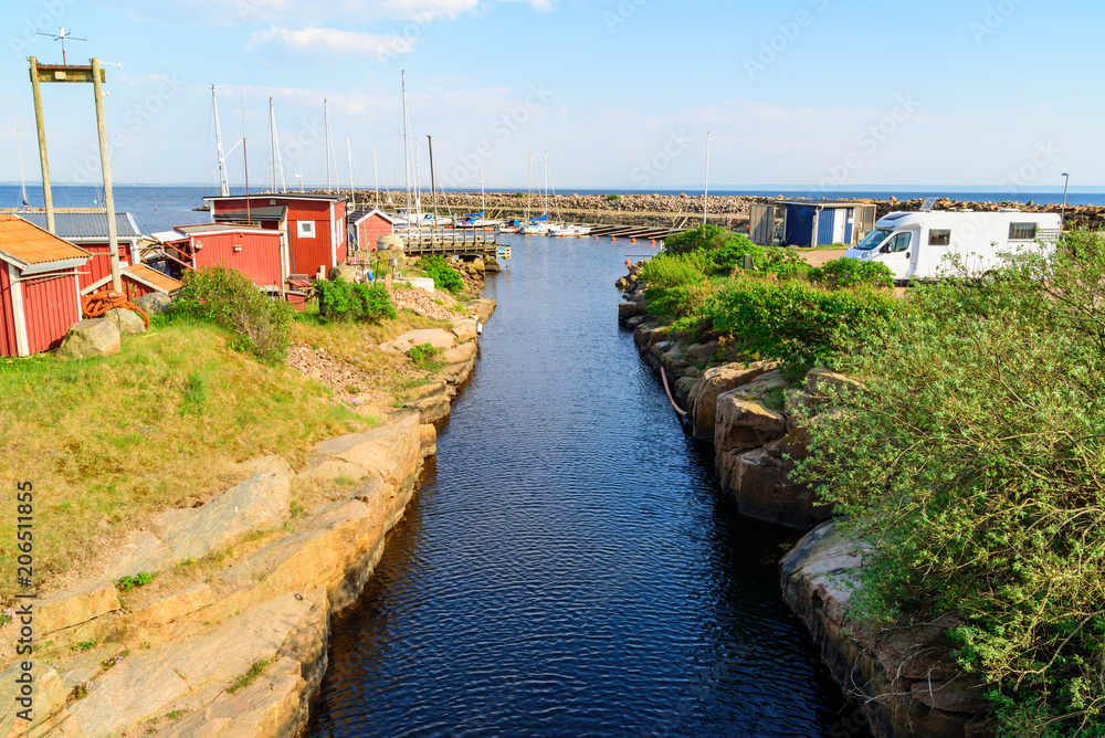 Narrow and straight canal at a marina in Grotvik, outside Halmstad, Sweden. Logos removed.