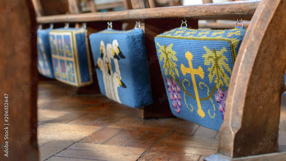 Embroidered Kneelers Prayer Cushions Hanging From Church Bench, shallow