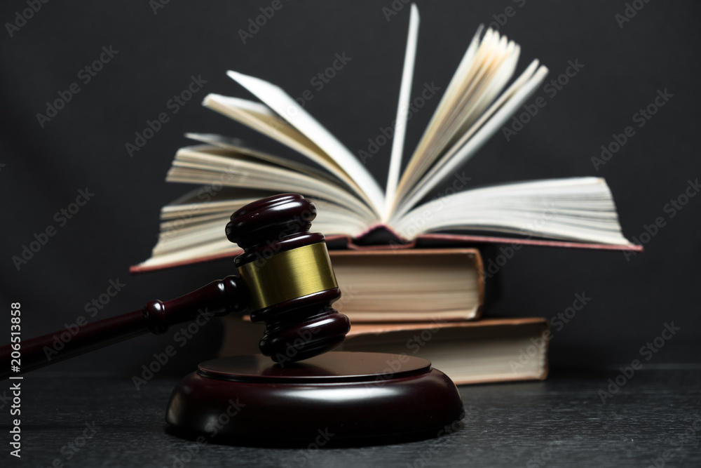 Judge gavel beside pile of books on wooden background Judge gavel beside pile of books on wooden background