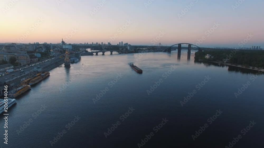 Barge sails along the river near the city port on sunset aerial footage Barge sails along the river near the city port on sunset aerial footage