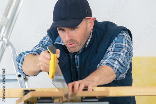 carpenter sawing wood with hand saw