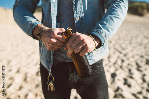 Man opening a bottle of beer on the beach