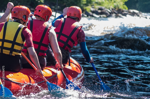 Quadro su tela Rafting in life jackets, men row oars on a catamaran