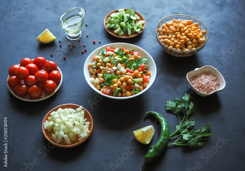 Summer vegetarian diet. Salad with chickpeas and vegetables on a black table.