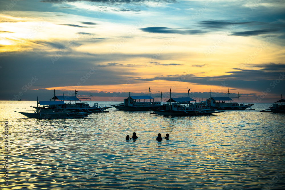 Swimming Tourists and Tour Boats in the Sea at Sunset