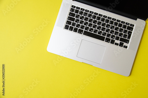 Flat lay with laptop on bright olive yellow background with copy space