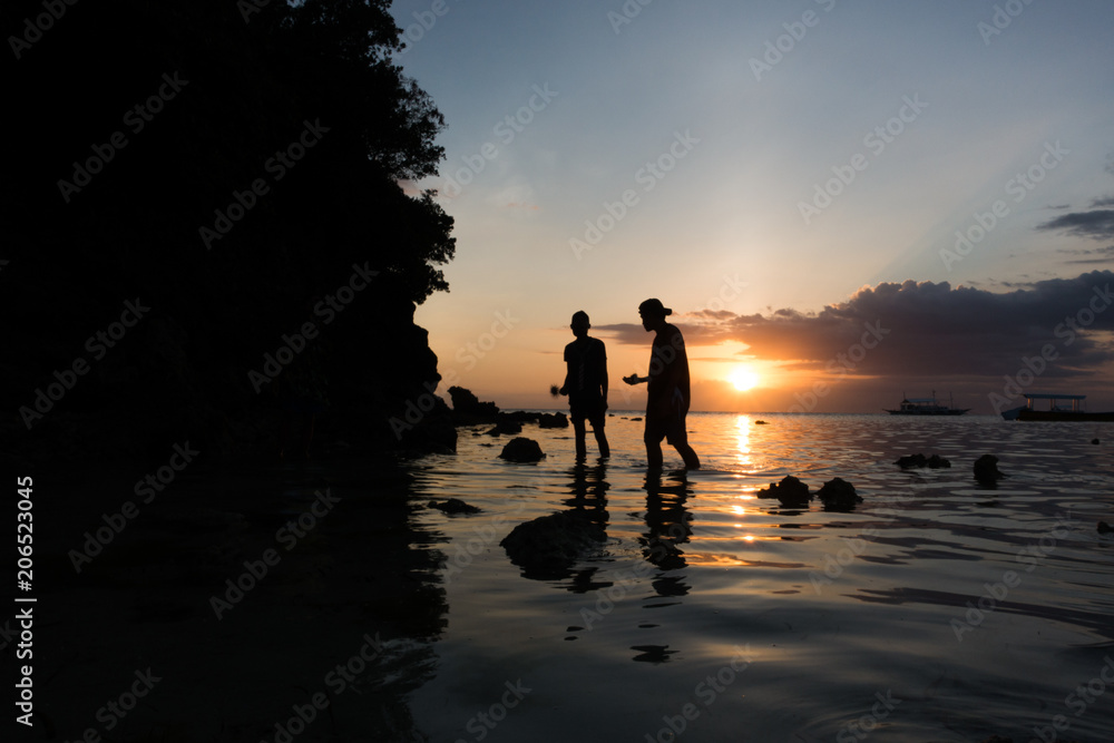 Fototapeta premium Sunset Friend Silhouettes on Rocky Island Beach