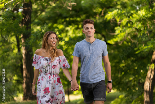 Smiling couple holding hands and walking in park. © Goran