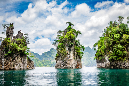 Mountain scenery with with tropical rain forest in the background and blue water lake in the foreground during a sunny day at Ratchaprapha Dam at Khao Sok National Park, Surat Thani Province, Thailand