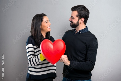 Couple holding a heart toy on grey background