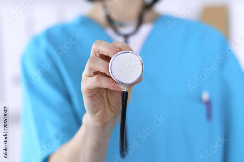 Female doctor holds stethoscope head closeup. Medical help and insurance in health care, best treatment and medicine concept