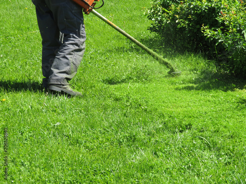 Gardener mowing the grass with manual lawn mower. Green lawn mowing