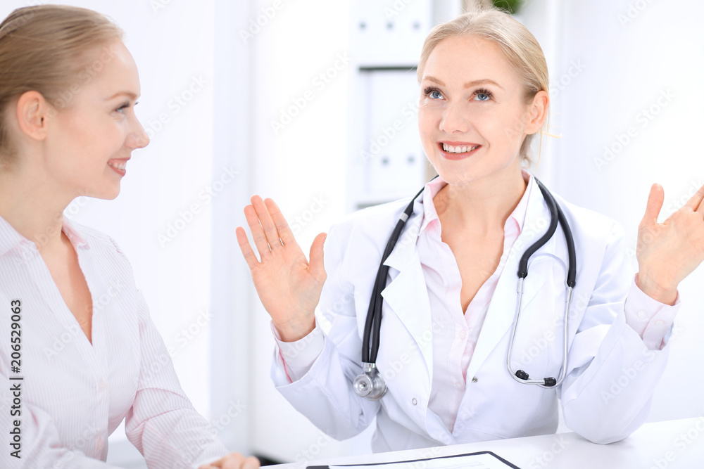 Blonde female doctor and patient talking in hospital office. Health care and client service in medicine Blonde female doctor and patient talking in hospital office. Health care and client service in medicine