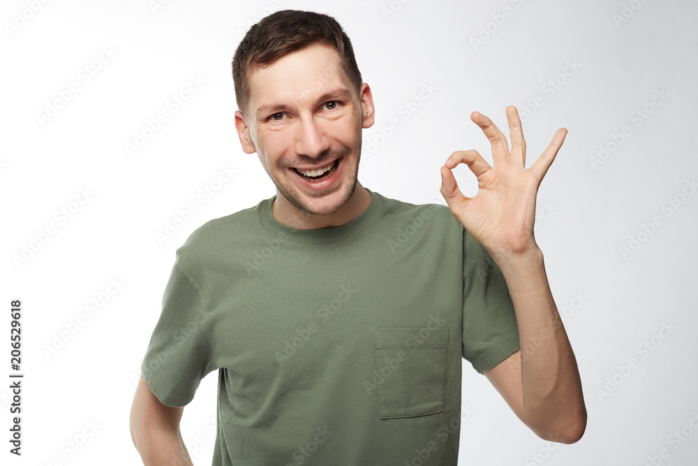 Fototapeta premium Attractive Caucasian man with beard opening mouth with joy showing ok sign being glad after meeting with woman he likes isolated over white background. Human facial expressions and emotions concept.