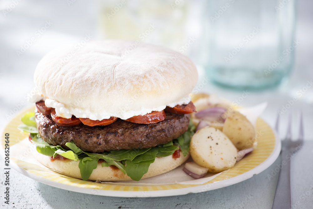 Beef burger with chorizo, goats cheese, rocket leaves and tomato relish, served with baby potato salad Beef burger with chorizo, goats cheese, rocket leaves and tomato relish, served with baby potato salad