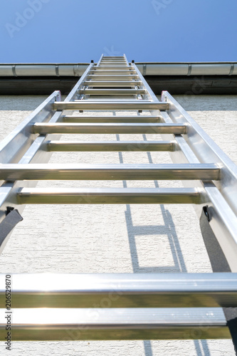 three section aluminum ladder leaning against house