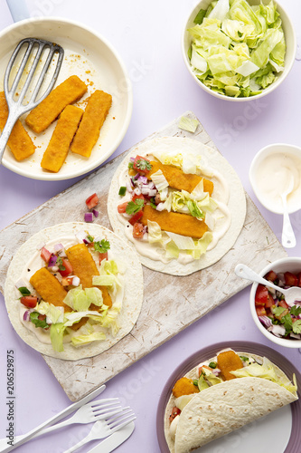 Fish fingers open tortillas tacos on spicy mayonnaise and lettuce with red onion, green & red pepper salad