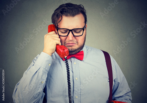 heartbroken sad man talking on telephone and looking unhappy feeling devastated