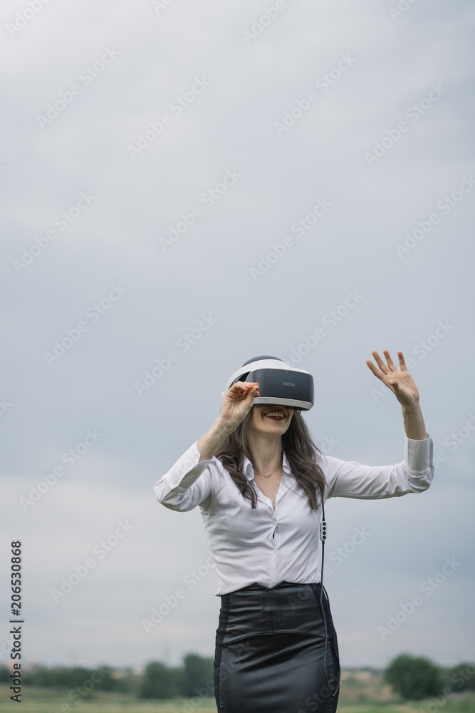 Beautiful brunette woman with virtual reality glasses, outdoors