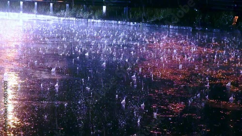 Large drops of rain fall on wet asphalt, rain on the road in the night city, headlights and city lights fend off in puddles on the roadway, slow motion